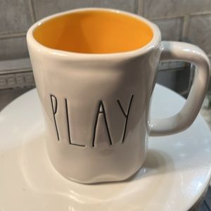 RAE Dunn mug.  Says PLAY. Lightish orange interior.